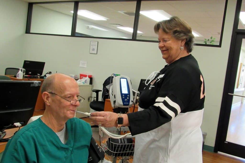 Unit Clerk Lynda Baker checks Nurse Manning Reed's vital signs.