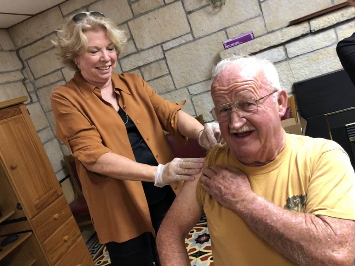 Evening Counselor Ed Johnson holds up his sleeve while Nurse Carol Thomas prepares to give him a flu vaccination.