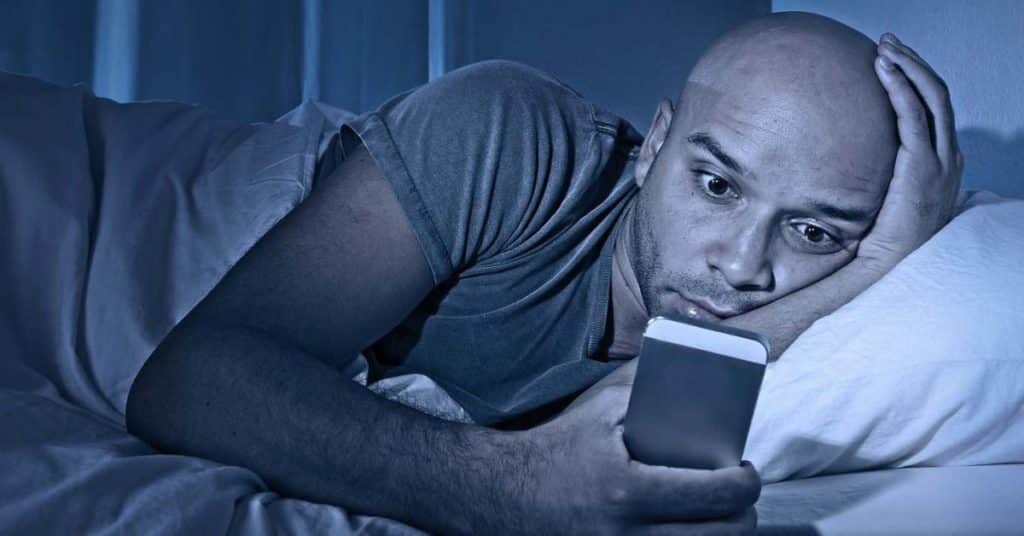 Young Cell Phone Addict Man Awake At Night In Bed Using Smartpho