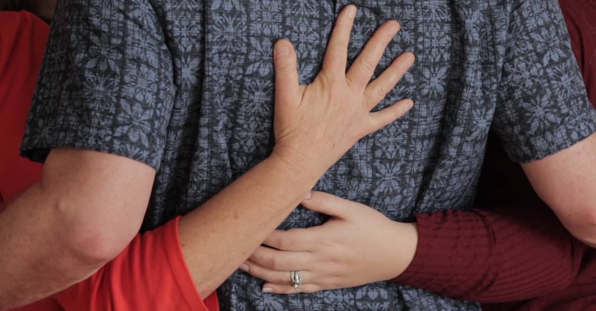 people in circle with arms linked behind backs