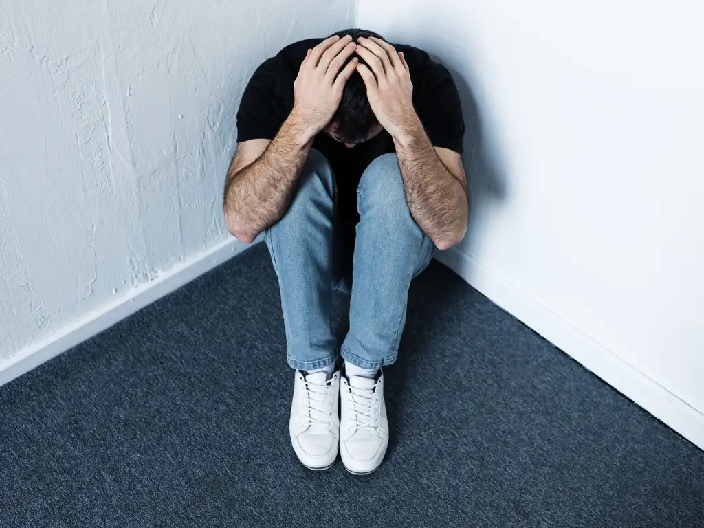 A person with depression sitting alone in a room, feeling overwhelmed by their mental health issues. | La Hacienda